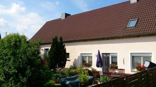 una casa con techo marrón, sillas y valla en Ferienwohnung Branitz, en Cottbus
