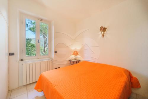 an orange bed in a white room with a window at Villa il Cappero View & Beach - Goelba in Procchio