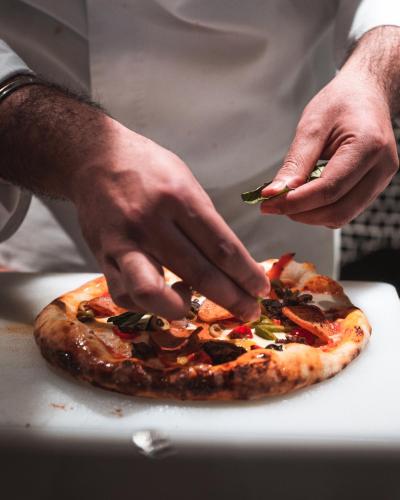 a man is preparing a pizza on a cutting board at The Khyber Himalayan Resort & Spa in Gulmarg