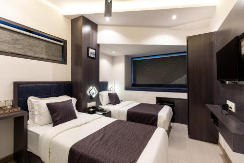 a hotel room with two beds and a flat screen tv at Hotel Larmont Luxury in Mumbai