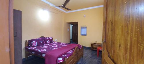 a bedroom with a bed with a purple blanket at Goroomgo Neelachal Holiday Nibasa Puri in Puri