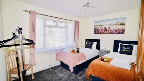 a hotel room with two beds and a window at E2M Stays Beautiful House Close To Heathrow Airport- Walking Distance To Thames River in Egham