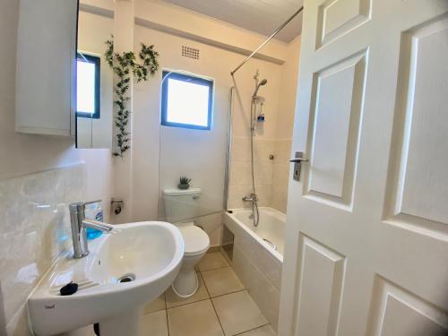 a white bathroom with a sink and a toilet at The Ultimate Escape - With Backup Electricity - Gaborone in Gaborone