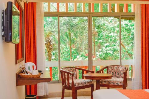 ナイロビにあるHotel Boulevard Nairobi, City Centre CBDの椅子2脚、テーブル、窓が備わる客室です。