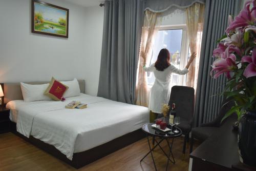 Hanoi Aria Central Hotel & Spa في هانوي: امرأة تبحث من نافذة غرفة الفندق