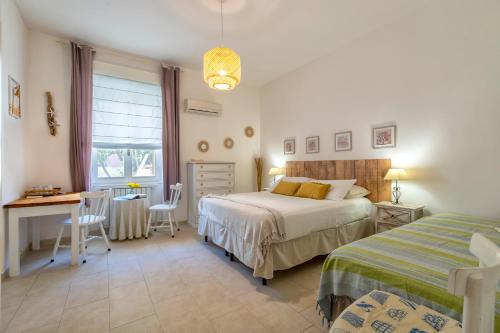 sypialnia z 2 łóżkami, stołem i biurkiem w obiekcie Affittacamere da Marianna w mieście Alghero