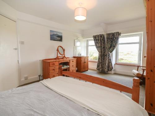 a bedroom with a bed and a dresser and a window at Dolafon in Pwllheli
