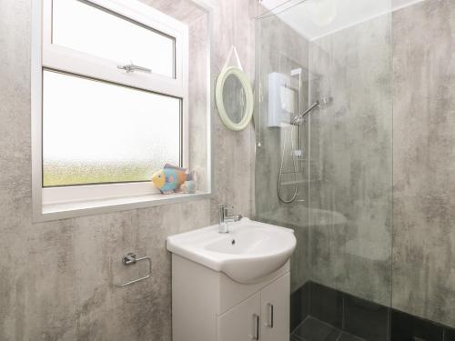 a bathroom with a sink and a shower and a window at Dolafon in Pwllheli