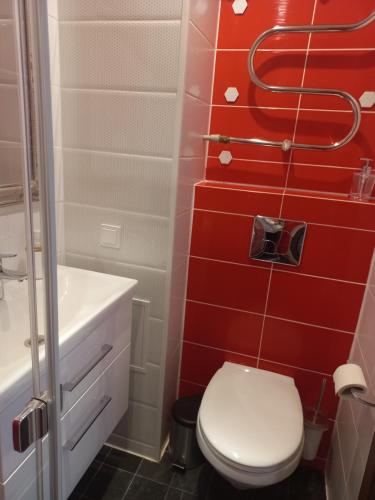 uma casa de banho com paredes vermelhas, um WC e um chuveiro em Vėtrungė center apartment em Klaipėda