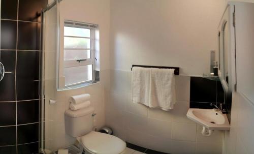 a white bathroom with a toilet and a sink at Two Door Cottage in Cape Town