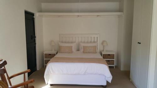 a bedroom with a large white bed with two tables at Two Door Cottage in Cape Town