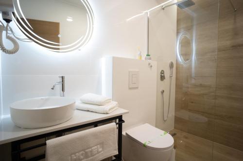 a white bathroom with a sink and a shower at Apartments and rooms SMILE in Mostar