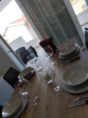 a wooden table with plates and wine glasses on it at Gioja suite in Quartu SantʼElena
