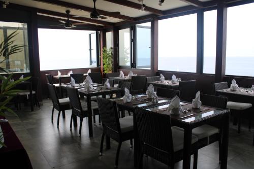 Beehive Premier في مدينة ماليه: غرفة طعام مع طاولات وكراسي ونوافذ