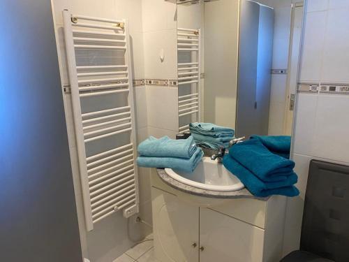 a bathroom with a sink with blue towels on it at Appartement face à la mer in Cap d'Agde