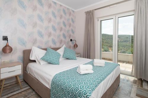 a bedroom with a bed with blue and white sheets and a window at ALMA HILLS Gialova in Gialova