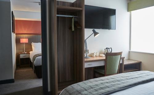um quarto de hotel com um quarto com uma secretária e uma cama em New Inn by Greene King Inns em Newport