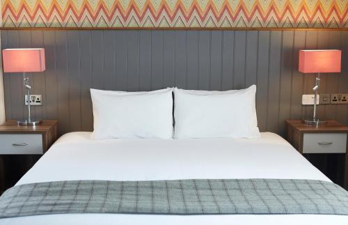 a bedroom with a white bed with two lamps at New Inn by Greene King Inns in Newport