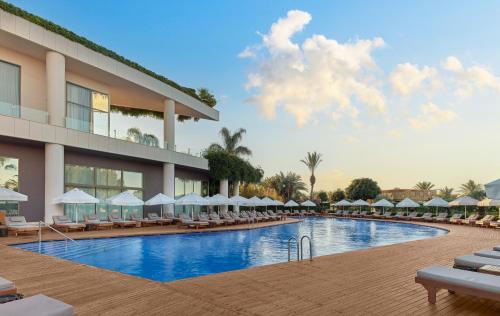 a resort swimming pool with lounge chairs and umbrellas at Maxx Royal Belek Golf Resort in Belek