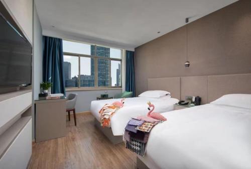 Yiwu Manting Hotel International Trade City义乌漫庭酒店 في ييوو: غرفة فندقية بسريرين وتلفزيون بشاشة مسطحة