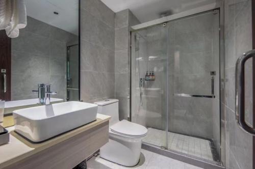 a bathroom with a shower and a toilet and a sink at Yiwu Manting Hotel International Trade City义乌漫庭酒店 in Yiwu