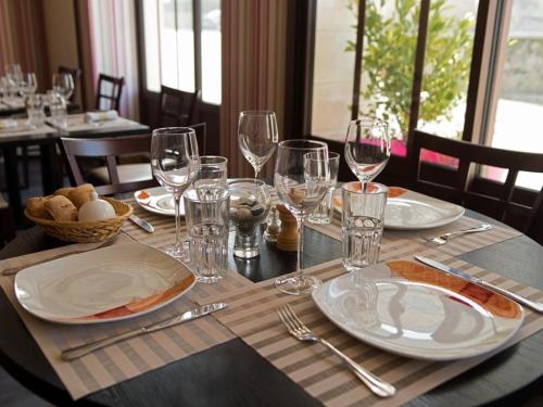 - une table avec des assiettes et des verres à vin dans l'établissement Le Petit Keriquel, à La Chapelle-Caro