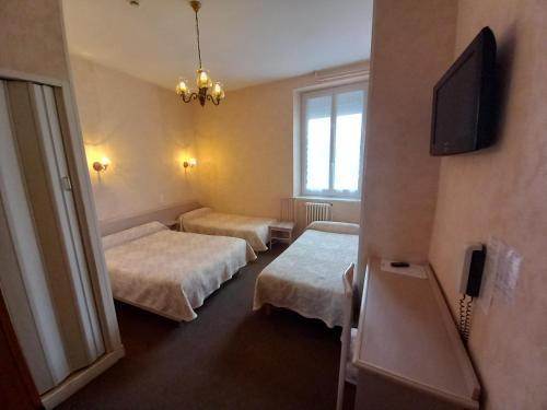 une chambre avec deux lits et une télévision à écran plat dans l'établissement Hôtel Hélios, à Lourdes