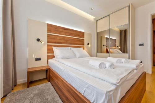 una camera da letto con un grande letto bianco e un grande specchio di Apartman MONTANA Vila Luna a Zlatibor