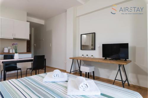 a room with a bed and a desk and a television at Anivia Apartments Airport by Airstay in Sp&aacute;ta