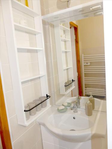 une salle de bain blanche avec un lavabo et un miroir dans l'établissement Appartement au pied des pistes, à Modane