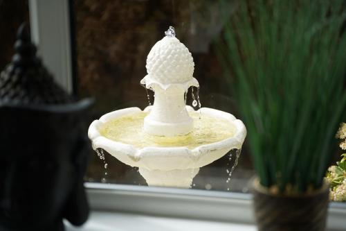 a white bird statue sitting on top of a water fountain at Bryn Derwen in Caernarfon