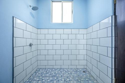 y baño con ducha de azulejos blancos y ventana. en Beach Jungalow en Marbella