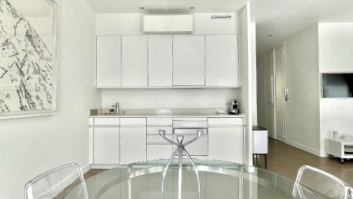 une cuisine avec une table en verre et des placards blancs dans l'établissement Arundel Croisette 100m Beach, Palais Free Parking AC Fibre, à Cannes