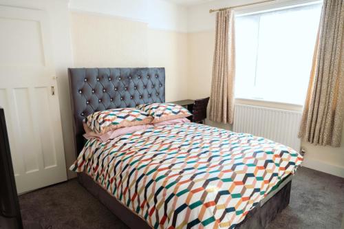 a bedroom with a bed with a blue headboard and a window at Exclusive 26 room in Ilford