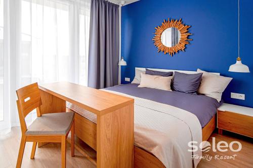um quarto com uma cama, uma secretária e um espelho. em Apartament Dwupoziomowy SUPERIOR z 2-sypialniami i klimatyzacją - SOLEO Family Resort em Rewal