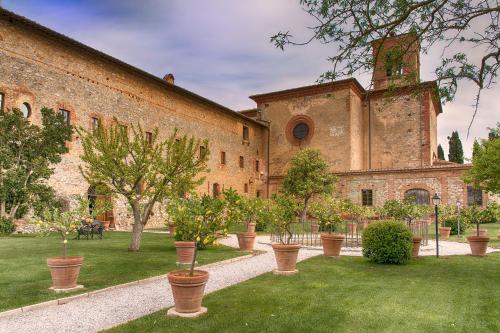 a large brick building with potted plants in a yard at Fattoria Monastero Sant'Anna in Camprena in Pienza