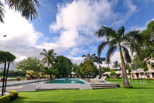 a swimming pool in a yard with palm trees at Shree Vilas Orchid By Lake Pichhola in Udaipur