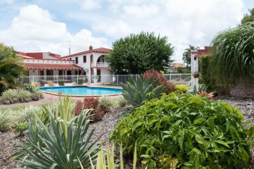 a swimming pool in a garden with plants at Bundaberg Spanish Motor Inn in Bundaberg