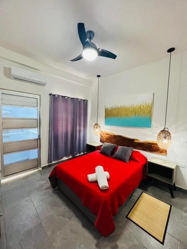 a bedroom with a red bed and a ceiling fan at Suites Maya Ka’an in Cancún
