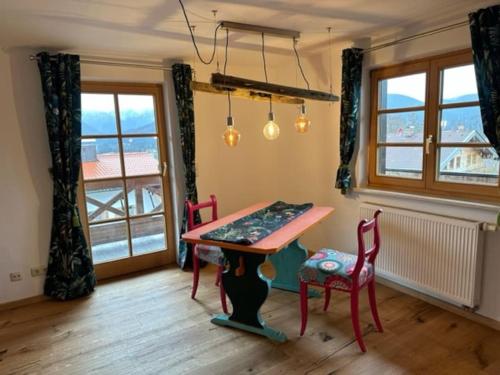 a dining room with a table and chairs and a window at Charmante farbenfrohe Wohnung für zwei in Fischbachau