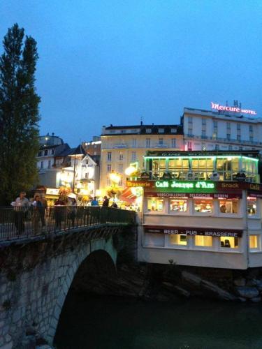 a bridge over a river with a building with lights at Appart'hôtel Saint Jean in Lourdes