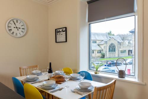 a dining room with a table and a clock on the wall at Wharfedale Retreat in Ilkley
