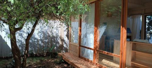 a building with a window next to a tree at Tribal Green Camp Private Room 1 in Santana