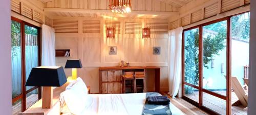 Cette chambre comprend un lit, une table et des fenêtres. dans l'établissement Tribal Green Camp Private Room 1, à SantʼAna