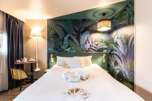 - une chambre avec un grand lit orné d'une peinture murale dans l'établissement Hôtel Grand Confort Le Moulin Rouge, à Terrasson