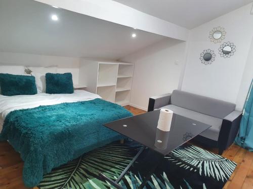 ein Schlafzimmer mit einem Bett mit einer grünen Decke und einem Tisch in der Unterkunft Joli studio/Bourget/CDG/PARIS in Aulnay-sous-Bois