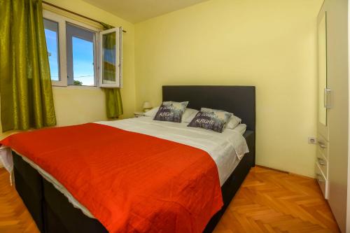 a bedroom with a large bed with a red blanket at Apartments Ercegovic in Rogoznica