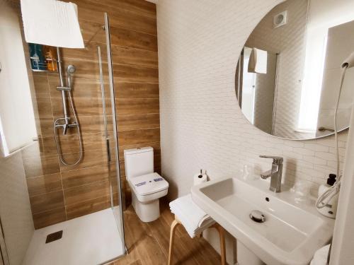 a bathroom with a shower and a toilet and a sink at PortoSantiago Boutique & Rooms in Portomarin