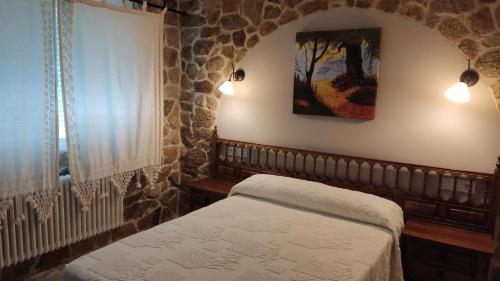 a bedroom with a bed and a stone wall at Casa Rural Outeiro in Outeiro