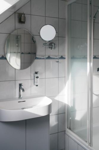 a white bathroom with a sink and a mirror at Schlei Hotel in Kappeln